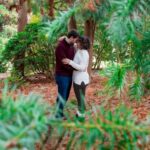 Couple hugging under large trees