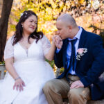 man kissing hand of woman on park bench